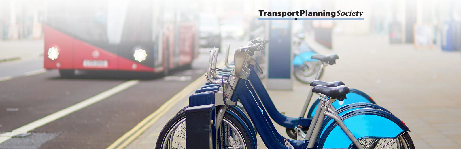 A row of blue bicycles on a London street with a London bus in the background